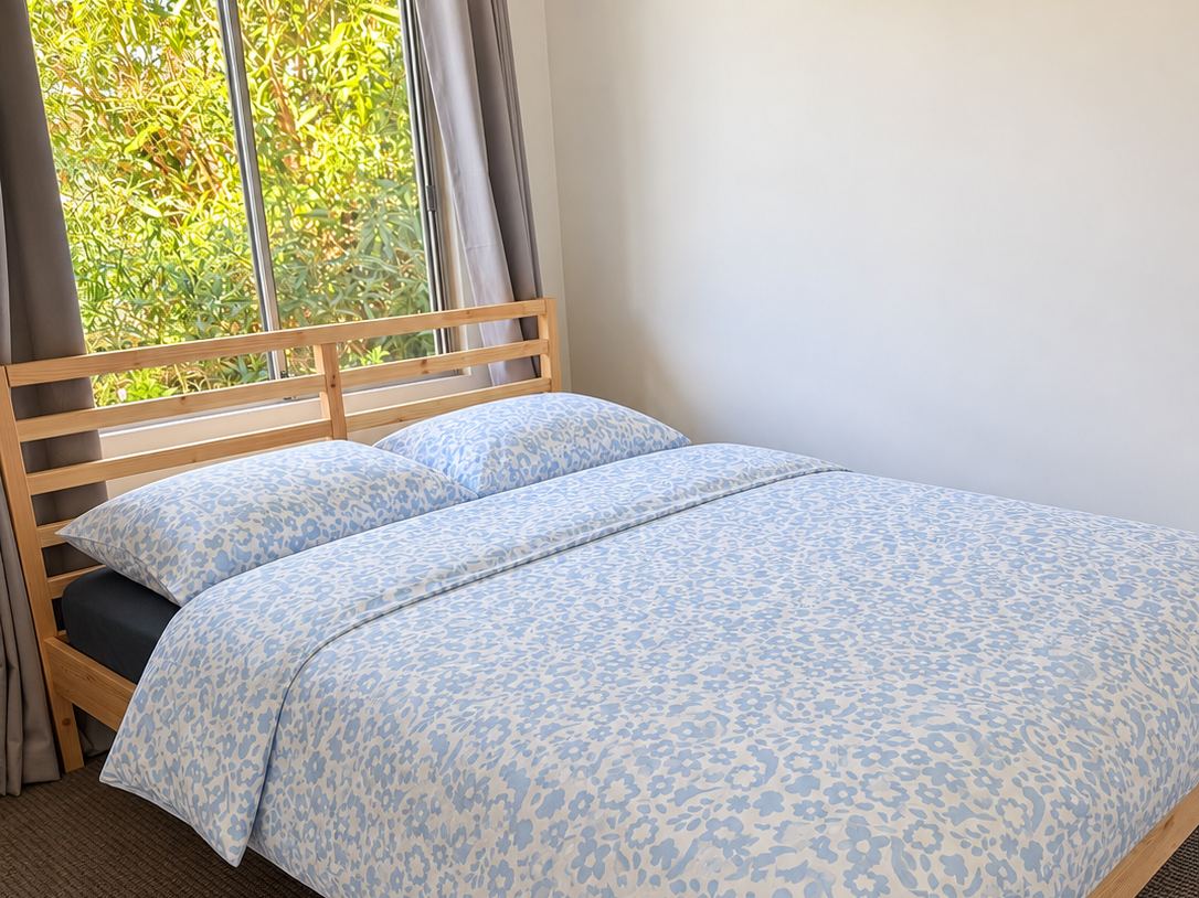 The Garden Room with queen bed and leafy window at Sandy Feet Retreat
