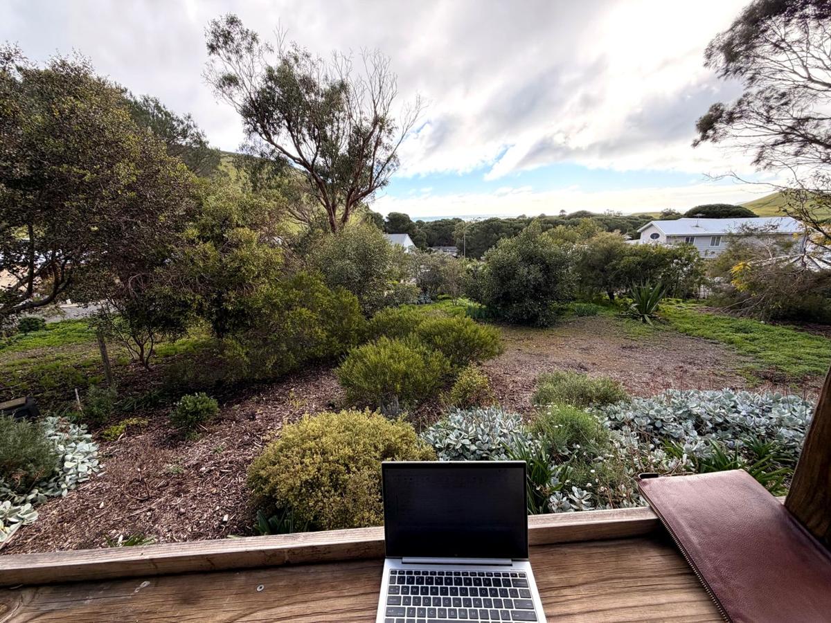 Laptop on the deck rail overlooking the garden and sea at Sandy Feet Retreat